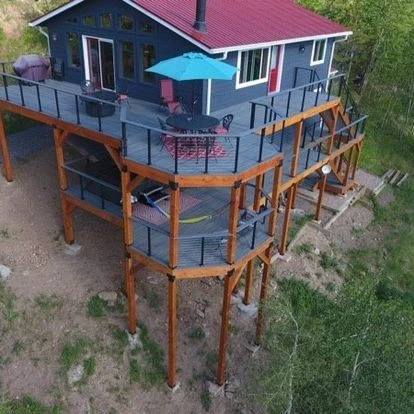 Backyard deck on uneven terrain with tall posts and a tiered design, showcasing safe, stylish hillside construction