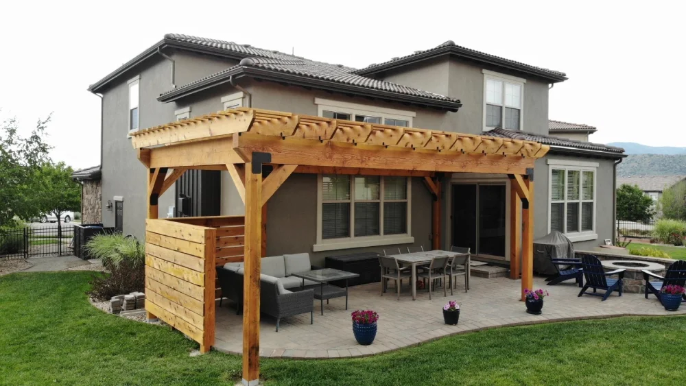 Backyard pergola attached to a modern two-story home with patio furniture underneath