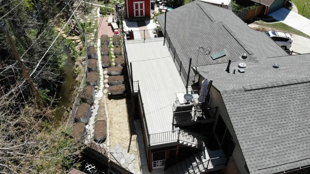 Drone shot of a modern residential deck installation with railing, patio furniture, and garden beds